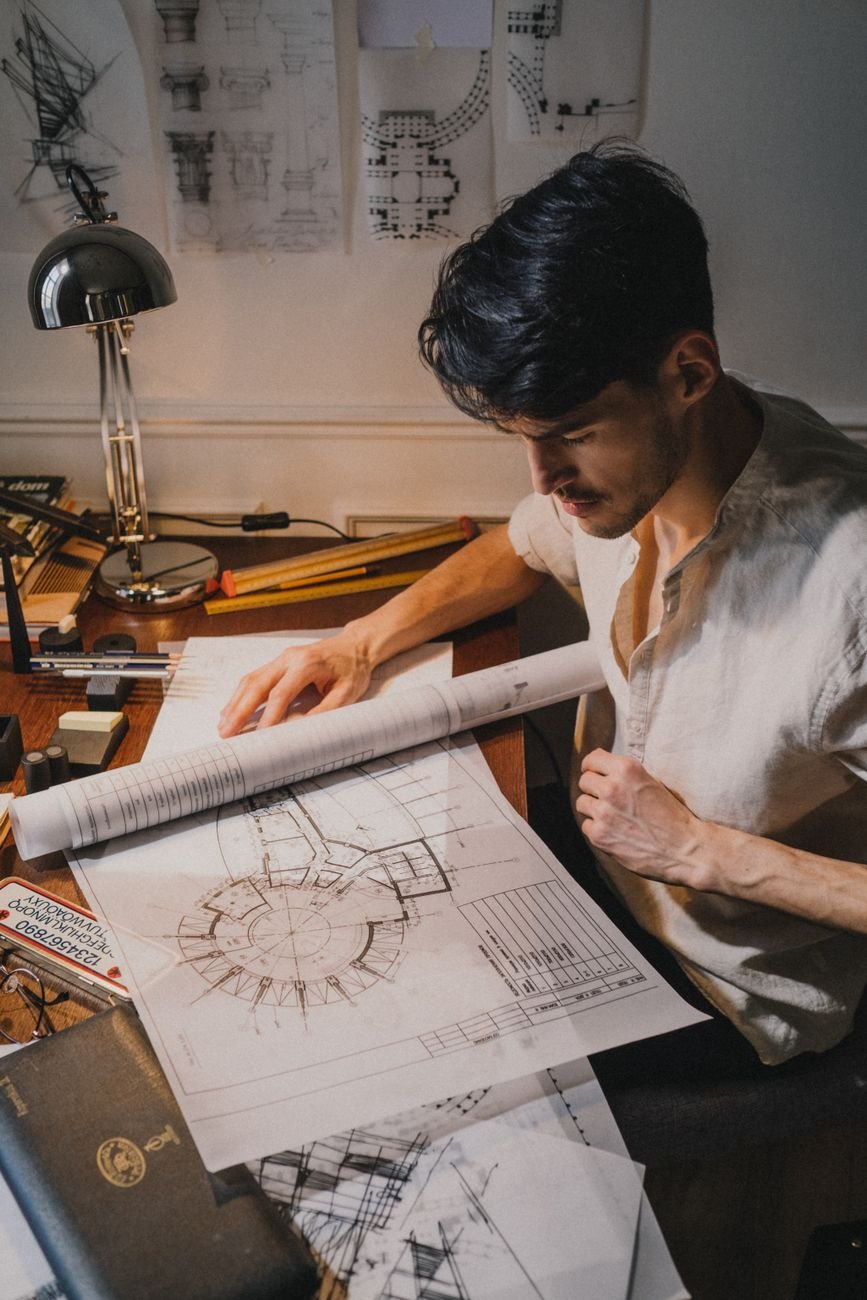 Architect reviewing architectural blueprints in a well-lit office environment.